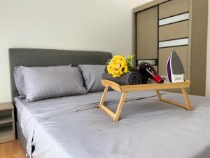 a tray on a bed with flowers and a mirror at The Platino By Antlerzone in Johor Bahru