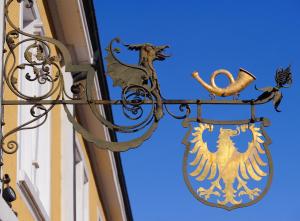 um sinal na lateral de um edifício com um escudo em Hotel Adler Post em Schwetzingen