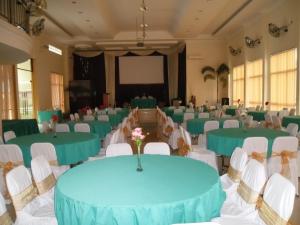 a banquet hall with green tables and white chairs at Permata Land Hotel & Resort in Rantauprapat
