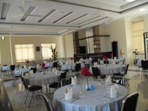 un salón de banquetes con mesas y sillas blancas en Permata Land Hotel & Resort, en Rantauprapat
