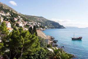 a boat on a body of water next to a mountain at Dubrovnik Sunset Apartments in Dubrovnik
