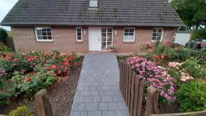 a house with a fence and flowers in front of it at Ferienwohnung Langfeld in Kronsgaard