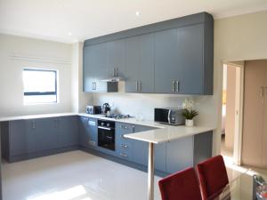 a kitchen with blue cabinets and red chairs at The Pickle Residence in Tzaneen