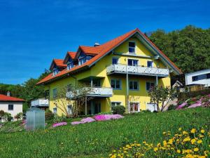 a yellow house with a red roof on a hill at Ferienhaus am Johannesbuhl in Waldmünchen