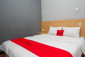 einem roten und weißen Bett mit zwei roten Kissen darauf in der Unterkunft RedDoorz near Exit Tol Batang in Pekalongan