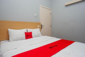 ein Schlafzimmer mit einer roten Decke auf einem weißen Bett in der Unterkunft RedDoorz near Exit Tol Batang in Pekalongan