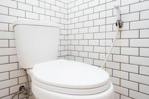um WC branco numa casa de banho com azulejos brancos em RedDoorz near Exit Tol Batang em Pekalongan