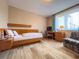 Cette chambre comprend un lit, un bureau et un canapé. dans l'établissement Hotel Landhaus Wörlitzer Hof, à Oranienbaum-Wörlitz