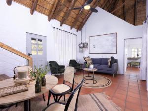 sala de estar con sofá azul, mesas y sillas en Simbavati Mvubu Cottage, en Reserva Timbavati