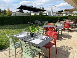 a group of tables with chairs and an umbrella at Campanile Villejust - za Courtaboeuf in Villejust