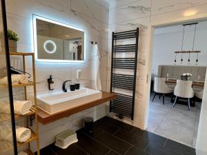 La salle de bains est pourvue d'un lavabo et d'un miroir. dans l'établissement JUNIPRO Luxury Apartments, à Nohfelden