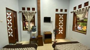 a bedroom with two beds and a tv and two windows at Homestay Candi Pawon Fahrurohman Syariah in Mendut