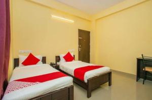 two beds in a room with red pillows at HOTEL SLN INN in Bangalore