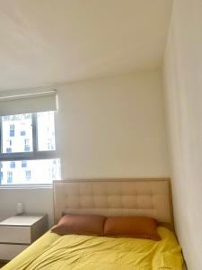 een slaapkamer met een bed met een gele deken en een raam bij Phòng riêng căn hộ SKY9 đầy đủ tiện ích in Ho Chi Minh-stad