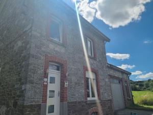 een bakstenen gebouw met een witte deur aan de zijkant bij Maison de vacances aux portes des Fagnes in Hamoir