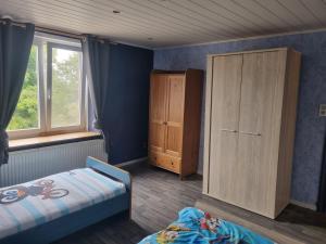 1 dormitorio con 2 camas, armario y ventana en Maison de vacances aux portes des Fagnes, en Hamoir