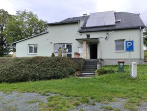 a white house with a solar panel on the roof at Apartmán U Švejdy in Skuhrov nad Bělou