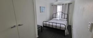 um pequeno quarto com uma cama e uma janela em North Coogee Beach House em Fremantle