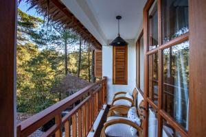 a balcony with chairs and a view of the forest at Tira Vilagna Suites & Spa in Kintamani