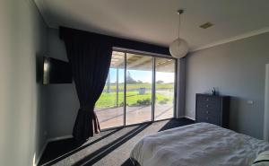 a bedroom with a bed and a large sliding glass door at Wheel chair & Pet Friendly Waterfront Retreat, 10 minutes to Phiilip Island, fireplace, wood supplied, WIFI wine & chocolates in Kilcunda