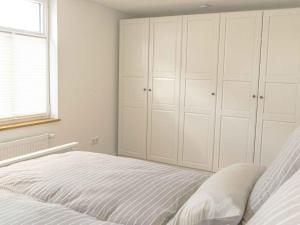 Schlafzimmer mit einem Bett mit weißen Schränken und einem Fenster in der Unterkunft Ferienwohnung Feldmann Auf der Mauer in Schmallenberg