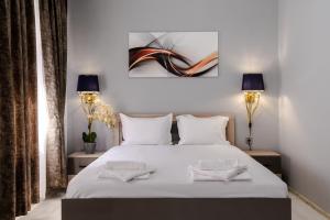 a bedroom with a large white bed with two lamps at Cappo Aparthotel in Veliko Tŭrnovo