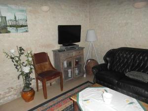ein Wohnzimmer mit einem schwarzen Ledersofa und einem TV in der Unterkunft GITE A LA FERME in Le Pin-Saint-Denis