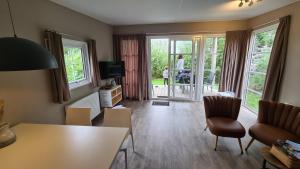 a living room with a table and chairs and a tv at Strand49 Glamping Sint Maartenszee in Sint Maartensvlotbrug