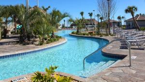 una piscina con sillas y palmeras en un complejo en Gorgeous 3Br Condo 10 min Disney, Golf Water Park en Kissimmee