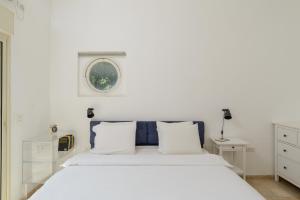 a white bedroom with a large bed and a window at Adorable 2 bedrooms apt w Bomb Shelter next to the beach in Tel Aviv