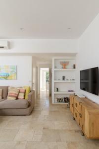 a living room with a couch and a tv at Adorable 2 bedrooms apt w Bomb Shelter next to the beach in Tel Aviv