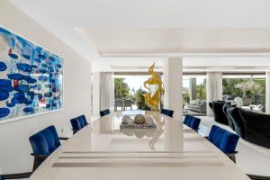 een eetkamer met een grote witte tafel en blauwe stoelen bij All About Villa Serenity in Marbella