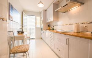 a kitchen with white cabinets and a table and a chair at Lovely Apartment In Costa Ballena in Costa Ballena