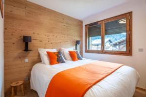 sypialnia z dużym łóżkiem i drewnianą ścianą w obiekcie Echo du Pleney B103 w mieście Morzine