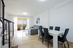 a dining room and living room with a white table and chairs at Residencial Playa de La Arena in Puerto de Santiago