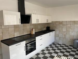 cocina con armarios blancos y encimera negra en Music Residence en Saarbrücken