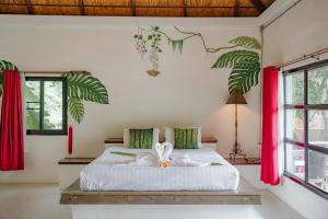 a bedroom with a large bed with red curtains at Karaboon Wellness in Phitsanulok