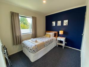 a bedroom with a bed and a blue wall at Apartment Style Holiday Home in Twizel