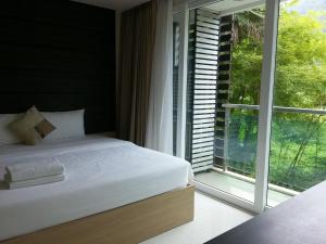 a bedroom with a bed and a large window at The Baycliff Residences in Patong Beach