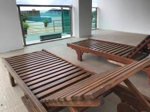 un banco de madera sentado en una habitación con una mesa en The Baycliff Residences, en Patong Beach