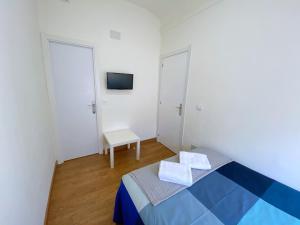 Cette petite chambre blanche dispose d'un lit et d'une télévision. dans l'établissement Apartamentos SmartRenting Justicia, à Madrid