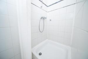 y baño con ducha de azulejos blancos y cabezal de ducha. en WHITE 60 QM Apartment - Zentral - Balkon - Messe, en Düsseldorf