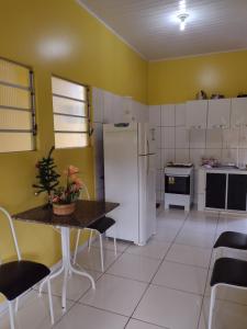 a kitchen with a white refrigerator and a table and chairs at Chalés Ponta de Pedras in Alter do Chao