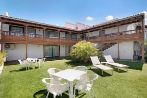 Un patio con mesas y sillas blancas frente a un edificio. en Linaje del Pago Negramol, en Sauzal