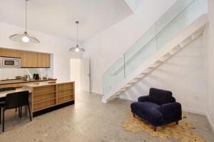 Una sala de estar con una escalera y una silla azul. en Linaje del Pago Negramol, en Sauzal