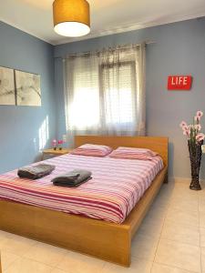 a bedroom with a large bed with striped sheets and a window at KOLOKOTRONIS’ HOUSE in Kavala
