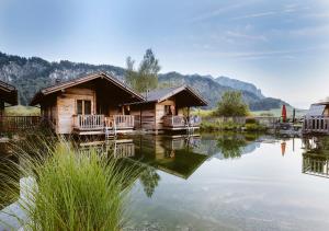 domek z bali nad jeziorem z górami w tle w obiekcie Golf- und Sporthotel Moarhof w mieście Walchsee