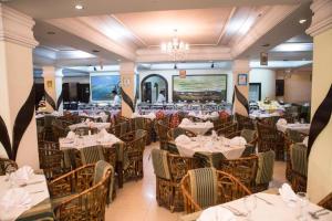 um restaurante com mesas e cadeiras brancas e um lustre em Meridian Hotel em Chittagong