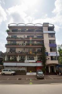 een hoog gebouw met auto's geparkeerd voor het bij Meridian Hotel in Chittagong