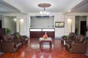 a lobby with leather chairs and a table with flowers on it at Meridian Hotel in Chittagong